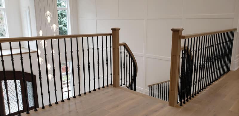 Upper landing with oak newel posts, handrail and iron balusters over wide-plank flooring