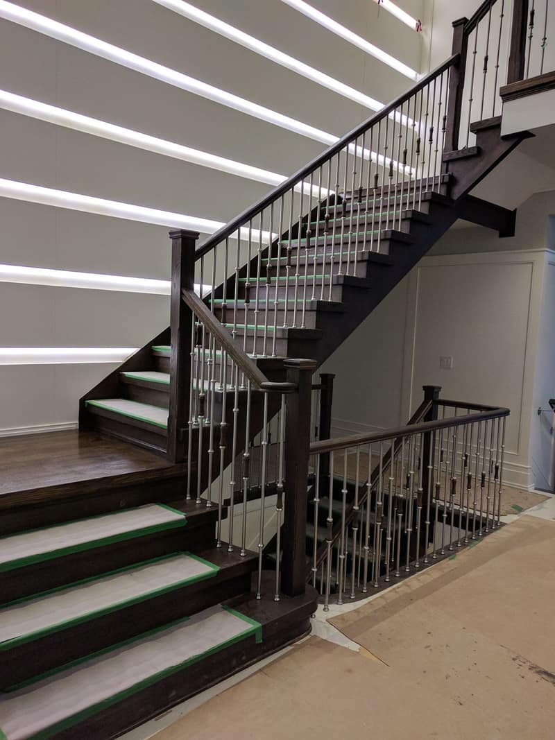 Staircase rebuild in progress with stained treads, iron balusters and protected nosings