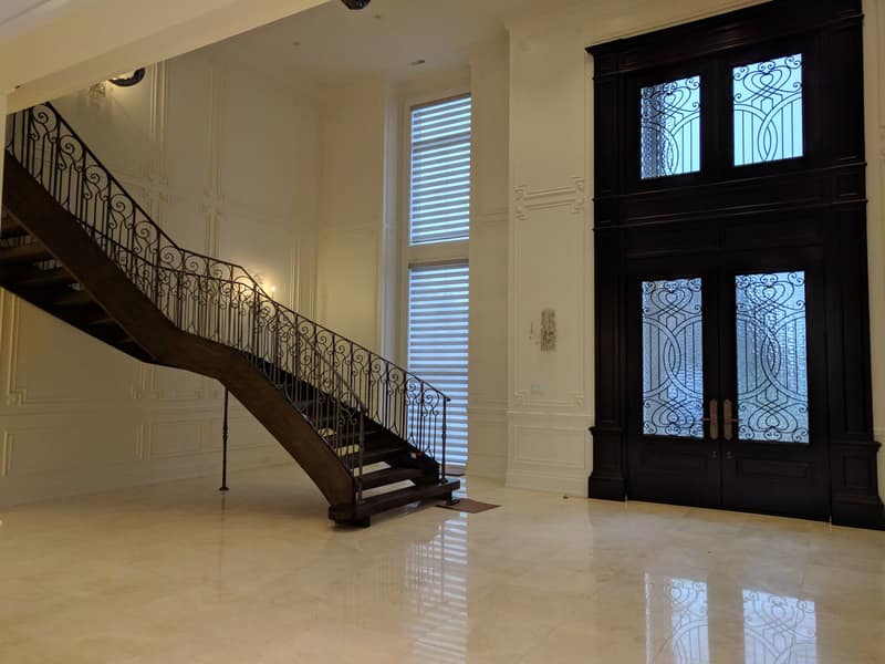 Grand foyer with a curved staircase, wrought-iron railing and polished floors