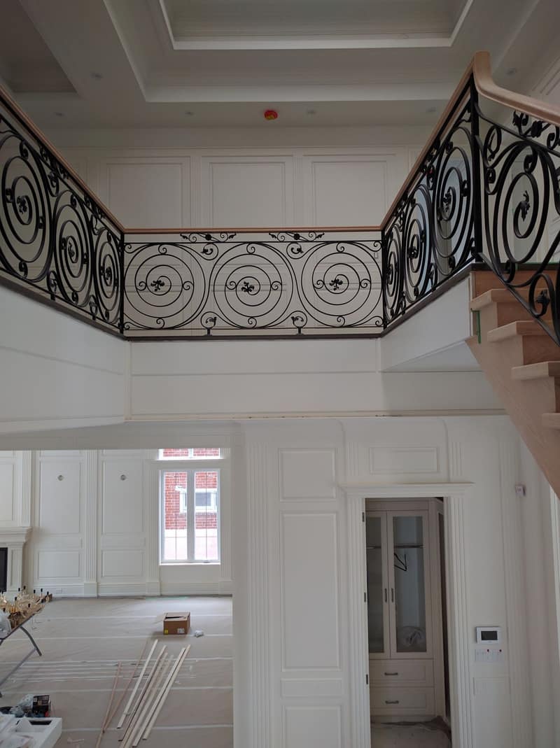 Upper hallway with a wrought-iron railing, panelled walls and a tray ceiling