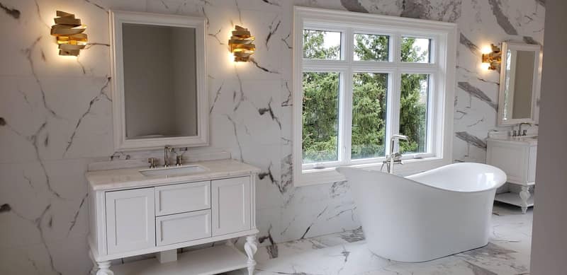 Ensuite bathroom with a freestanding tub, marble-look porcelain walls and a white vanity