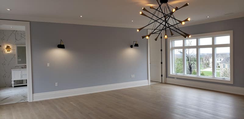 Primary bedroom with soft-grey walls, crisp white trim and wide-plank hardwood floors