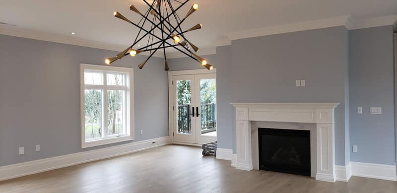 Freshly painted living room with a fireplace surround, crown moulding and hardwood floors